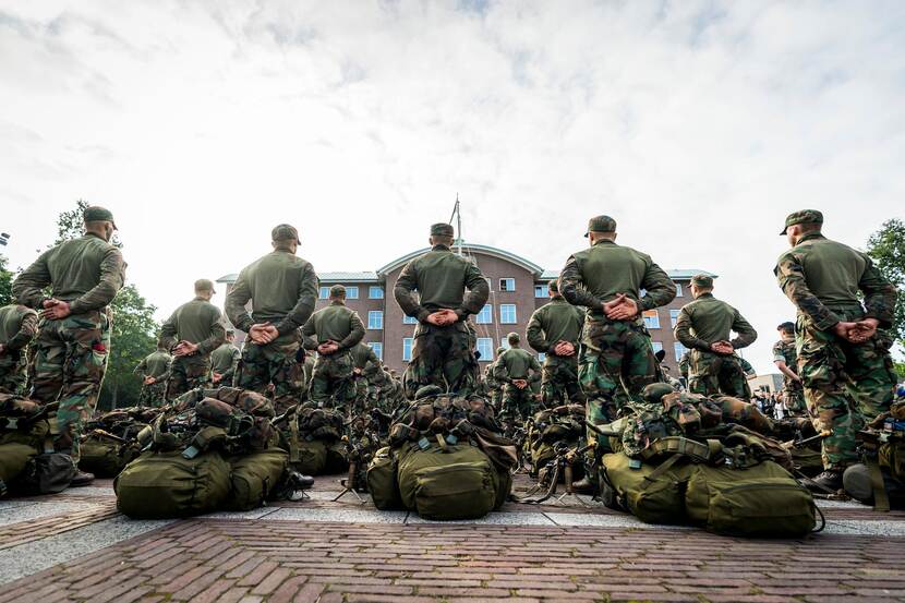 Militairen op de rug gezien met achter hen hun plunjebaal en militaire uitrusting.