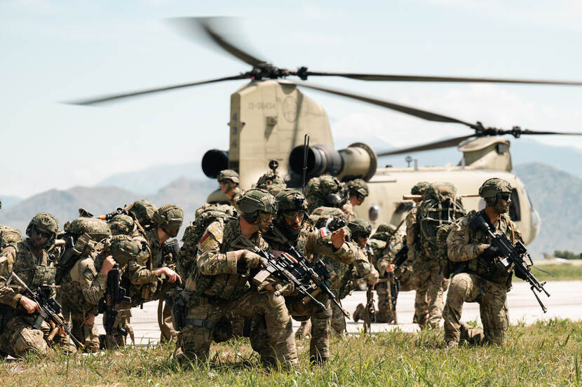 Groep bewapende militairen voor een Chinook.