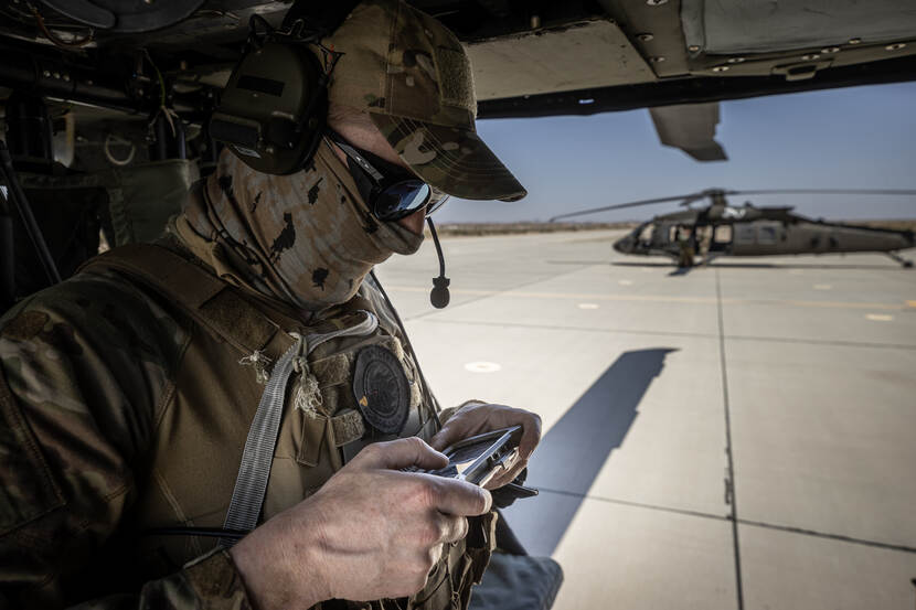 Een militair kijkt vanuit een helikopter op een scherm.