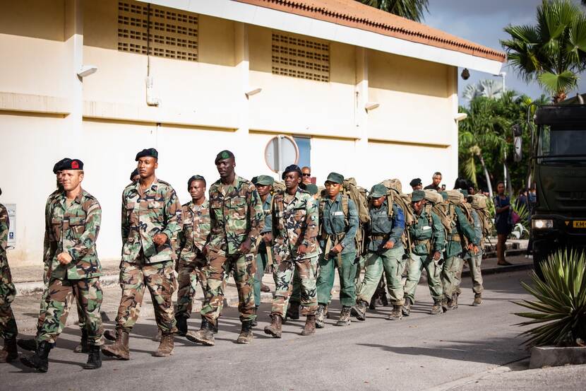 Groep Curaçaose mannen in uniform marcheren.