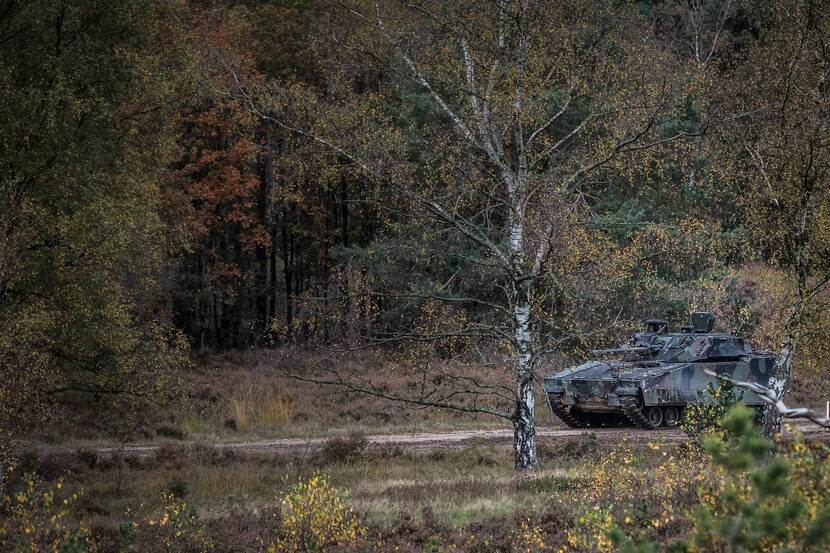 Tank rijdt door bosgebied.