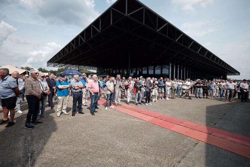 Veel mensen bij elkaar luisterend naar toespraak.