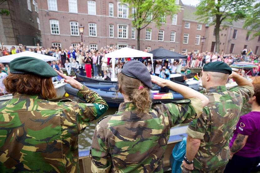 3 militairen brengen een eregroet aan applaudiserend publiek op de kade.