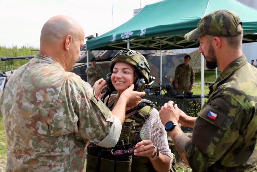 Militairen helpen jongen  met opzetten koptelefoon.