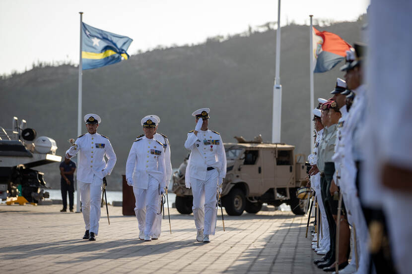 3 Marine-officieren lopen langs rijen personeel.