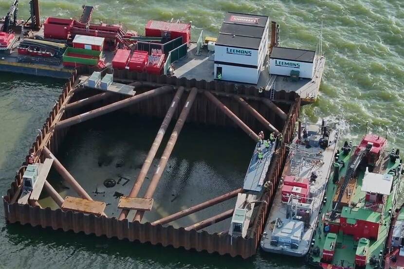 Luchtfoto van een platform met containers, materiaal en aangemeerde werkboten op het IJsselmeer.