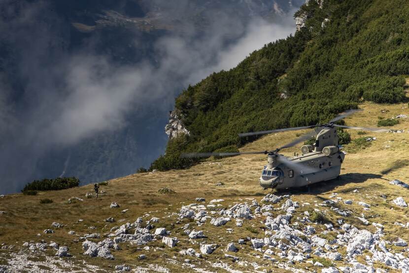 Een Chinook-transporthelikopter staat op de grond in bergachtig gebied.