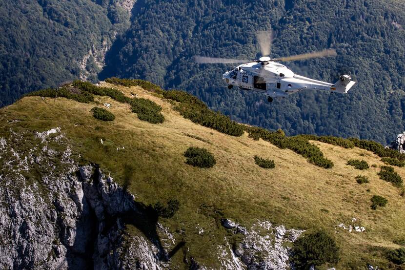 Een NH90-maritieme helikopter vliegt boven bergachtig gebied.