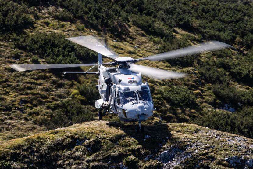 Een NH90-maritieme helikopter vlak boven bergachtig gebied.