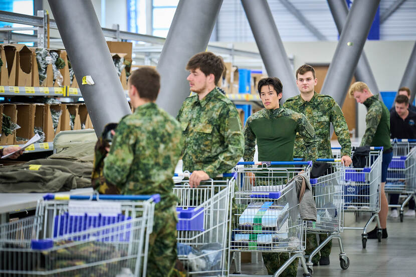 Jongeren in camouflagepak met boodschappenwagens met daarin dozen en kleding.
