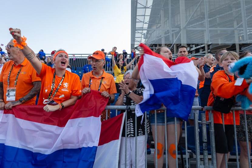 Juichende familie en vrienden met Nederlandse vlaggen achter dranghekken.