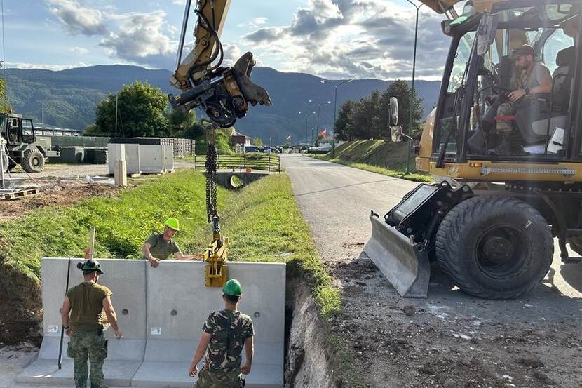 Een betonnen plaat wordt op z'n plek gehesen, naast een weg in Bosnië.