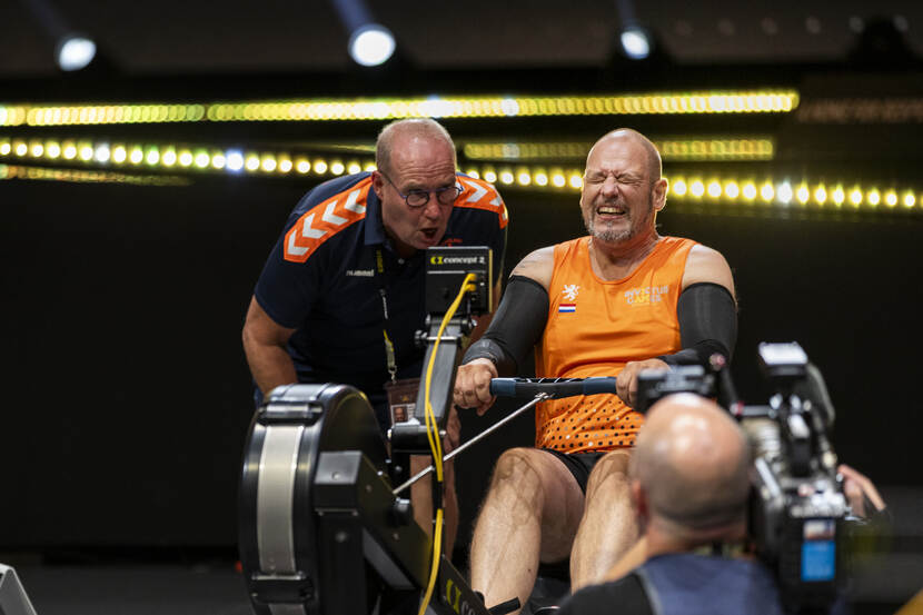 Coach André Wijnberger moedigt een Nederlandse indoorroeier aan.