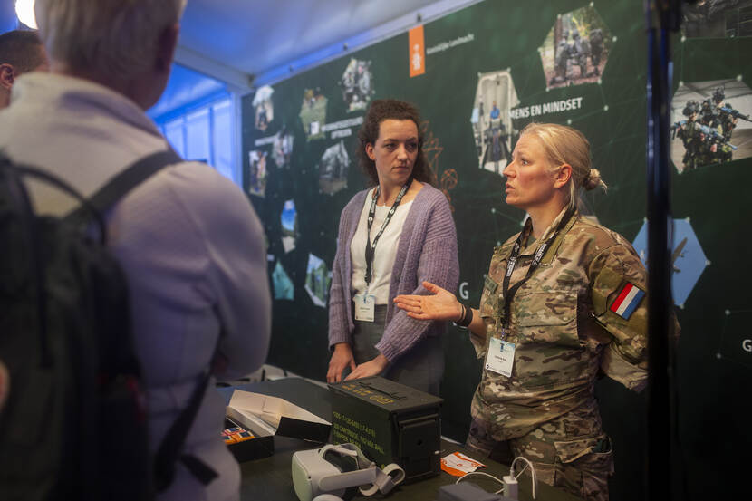 Militair en burgermedewerker achter een stand.