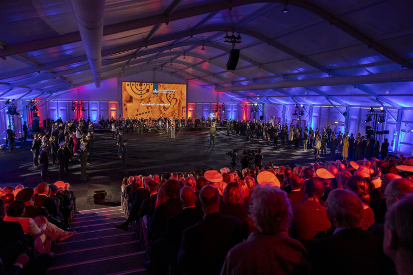 De commandowisseling op Kamp Soesterberg. Genodigden in de zaal en op tribune kijken toe.