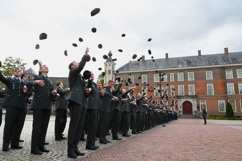 Militairen gooien petten de lucht in.