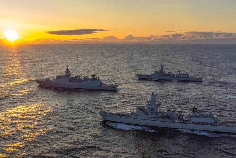 3 marinefregatten op zee bij ondergaande zon.