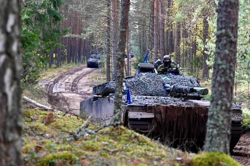 Militaire voertuigen rijden door een bos.