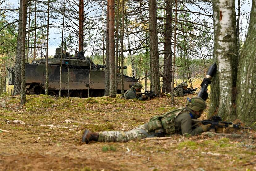 Militairen op de grond in het bos.