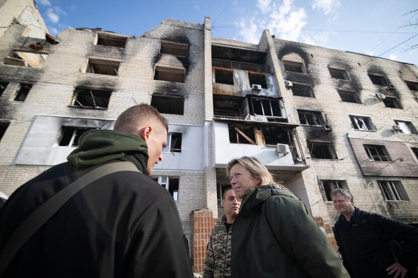 Minister Ollongren in gesprek, staand voor een geruïneerde flat.