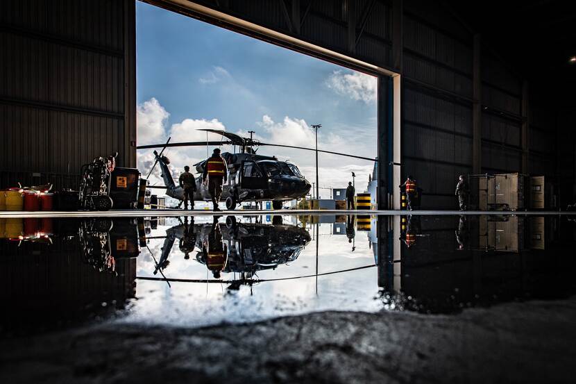 Een Amerikaanse Black Hawk-helikopter voor een hangaar.
