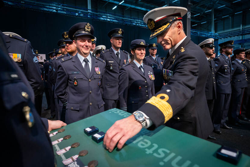 Blad met medaille met het opschrift ‘Forward Presence’. Militairen staan klaar om de medaille te ontvangen.