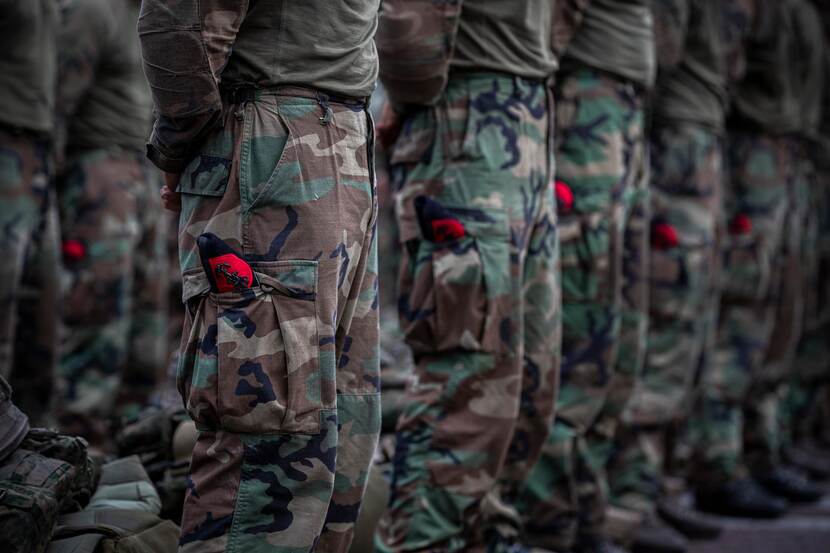 Benen van rij mariniers. Baret steekt uit broekzak.