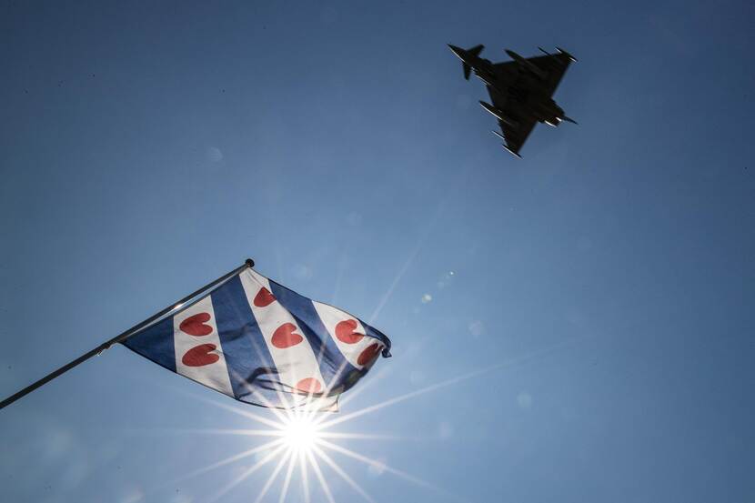 Een Duitse Eurofighter en een Friese vlag tegen een strakblauwe lucht.