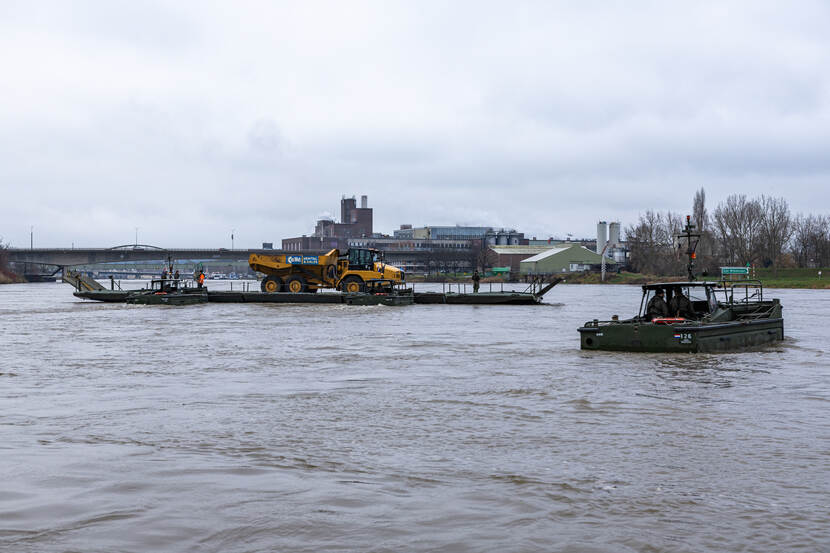 Door militairen snel opgezette veerverbinding verplaatst zwaar voertuig over rivier.