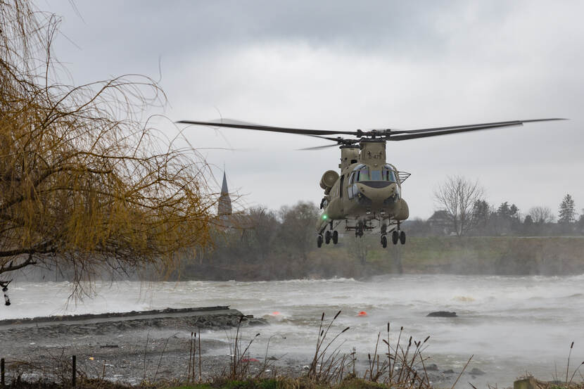 Chinook hangt boven overlaatdam om gat te vullen.