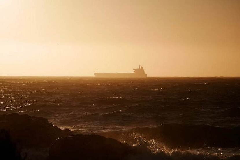 Containerschip op zee bij ondergaande zon.