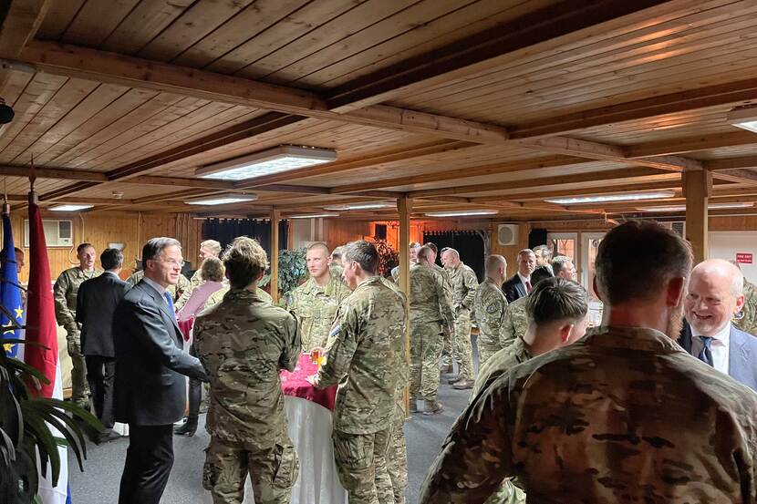 Premier Mark Rutte praat aan statafel met militairen.