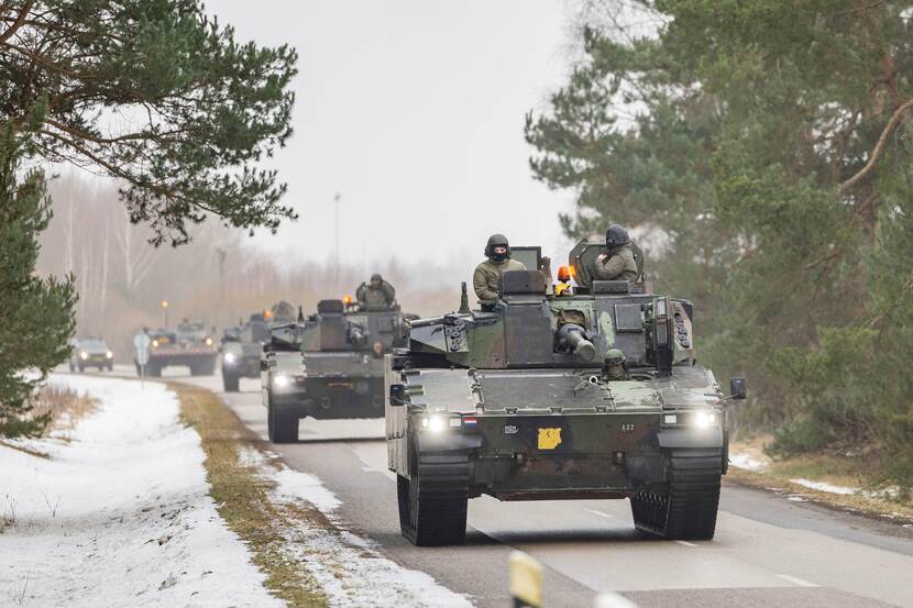 Colonne militaire voertuigen op besneeuwde weg.