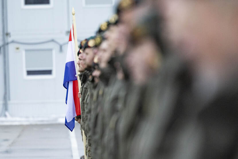 Militairen op rij met Nederlandse vlag.