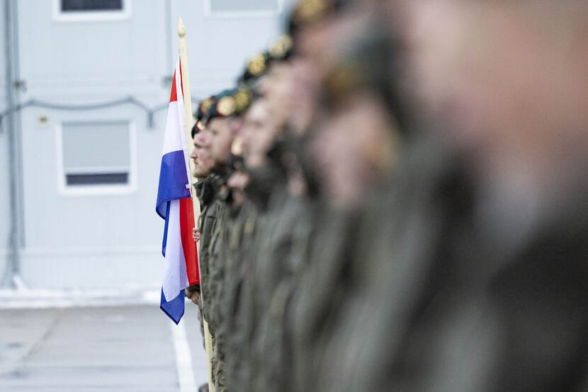 Militairen in een rij met de Nederlandse vlag.