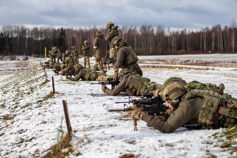Militairen in Litouwen schieten liggend in de sneeuw hun wapens in.