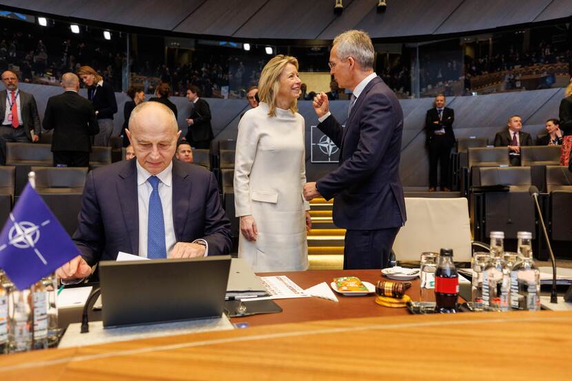 Minister Ollongren in gesprek met secretaris-generaal Stoltenberg achter een man die op een laptop werkt.