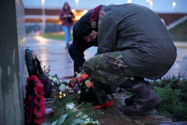 Bewoners en personeel leggen een bloemstuk bij het Waalcrossingmonument.