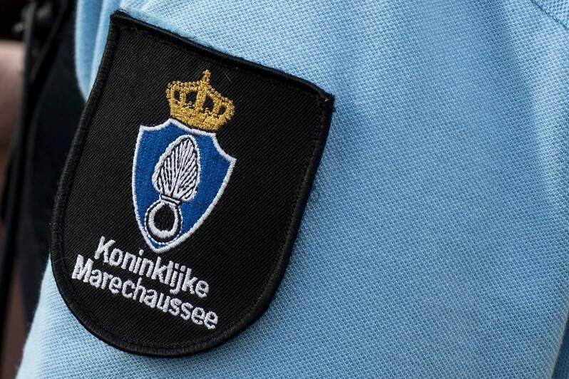 Het embleem van de Koninklijke Marechaussee op de schouder van een overhemd.