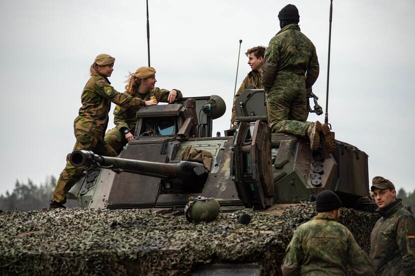 Militairen staan boven op een militair voertuig.