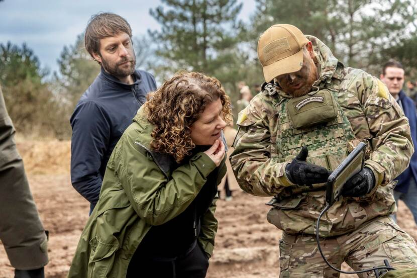 Militair geeft uitleg aan Kamerlid door iets op iPad te tonen.