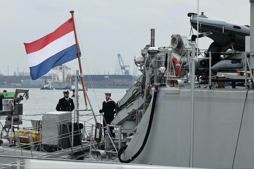 Bemanningsleden van de Vlaardingen halen de Nederlandse vlag naar beneden.