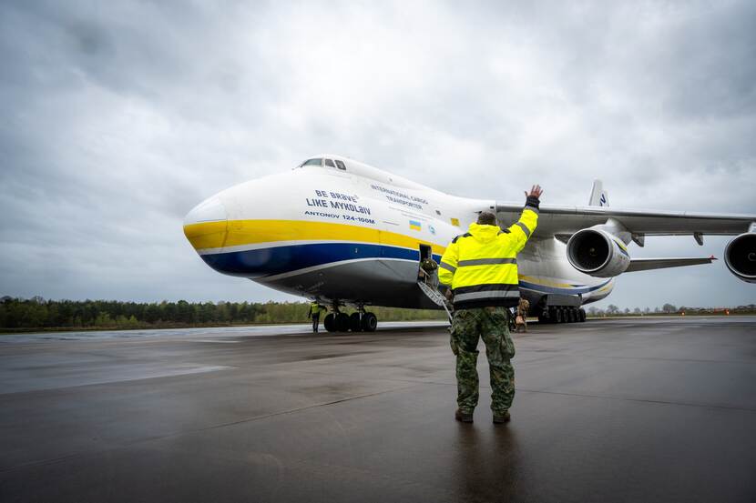 Antanov-vliegtuig. Militair in gele hes heeft arm omhoog.