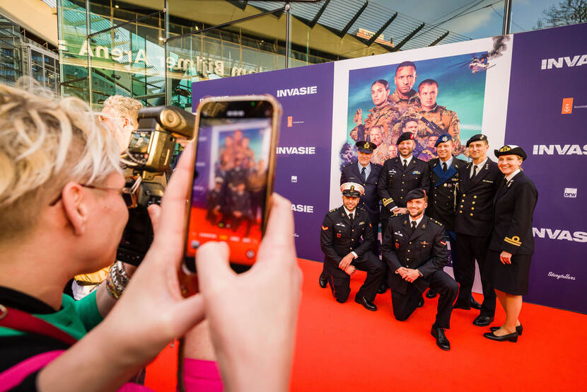 Vrouw maakt met smartphone een foto van marinepersoneel.