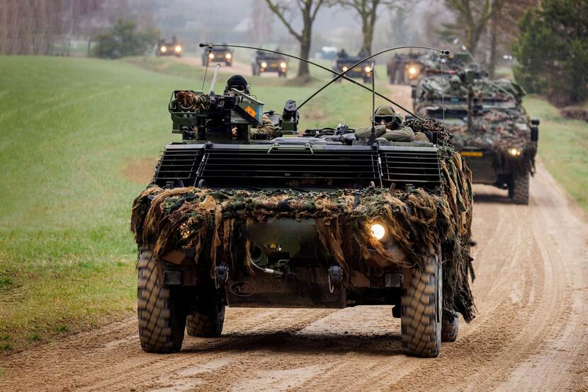 Colonne militaire voertuigen rijden over zandweg .