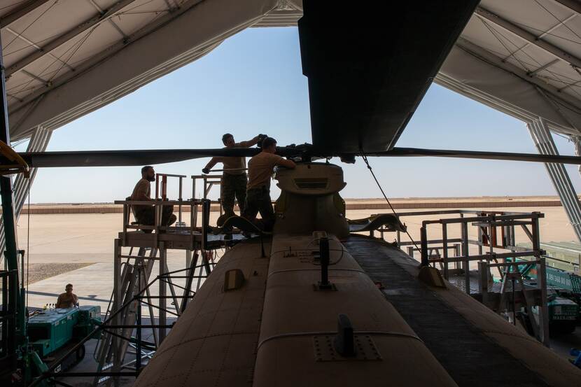 Militairen werken aan Chinook in shelter. Tegen achtergrond van blauwe lucht.