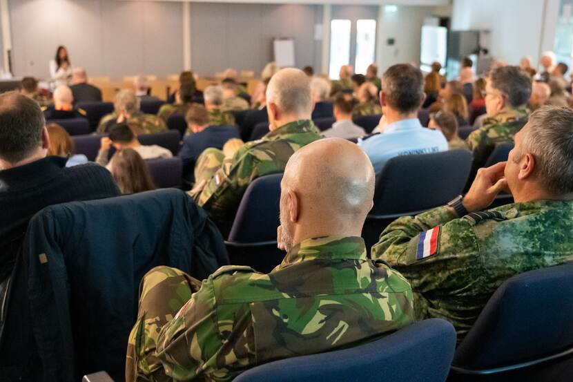 Militairen in een zaal vanaf de rug gezien.