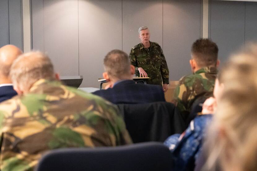 Een militair spreekt een zaal toe.