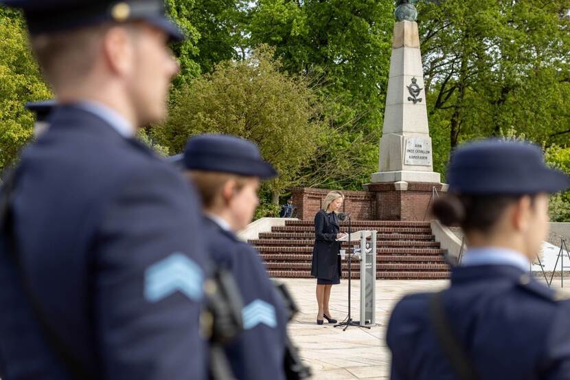 Minister Kajsa Ollongren achter spreekgestoelte met op achtergrond luchtmachtmonument in Soesterberg.