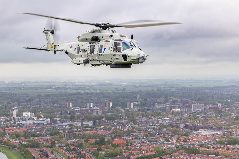 NH90-transporthelikopter vliegt boven Nederlandse stad.